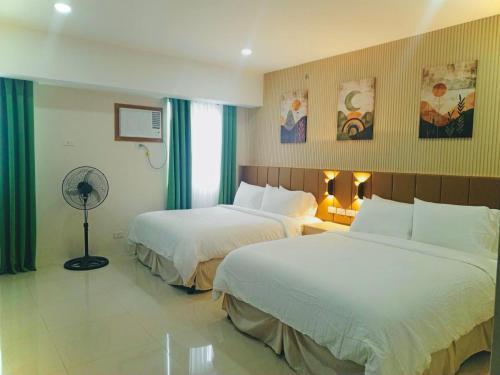 a hotel room with two beds and a fan at Baba Staytion 1-2-3 of SMDC Style Condo in Iloilo City