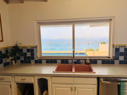 a kitchen sink and a window with a view of the ocean at A Newly Renovated Luxury 4 Bed Villa in Tortola Island