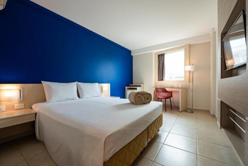 a bedroom with a large bed with a blue wall at Ibis Styles Macaé in Macaé