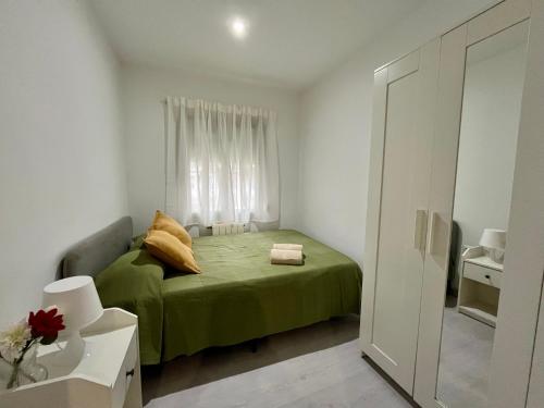 a small bedroom with a green bed and a window at Habitación privada en apartamento compartido junto al Aeropuerto y Fira Barcelona in El Prat de Llobregat