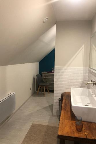 a white bathroom with a sink and a chair at Gite de collandres in Cheylade