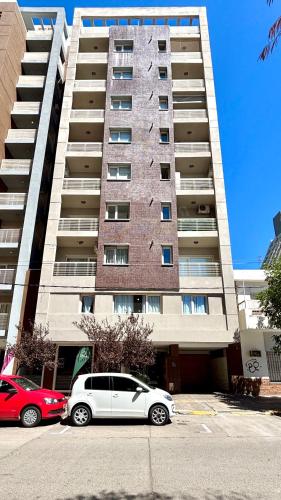 two cars parked in front of a tall building at Amoblado Temporal M&S 5 M in Neuquén