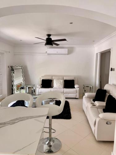 un soggiorno con mobili bianchi e un ventilatore a soffitto di Villa Ray a Gros Islet