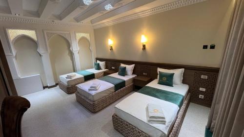 a room with three beds in a room at Shams Boutique Hotel in Bukhara