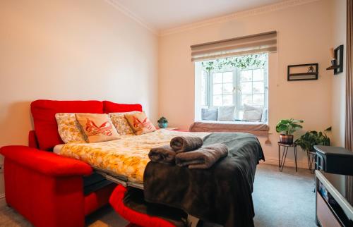 a bedroom with a bed and a red couch at Cozy 1BR Seaside Apt in Brighton Marina Village in Brighton & Hove
