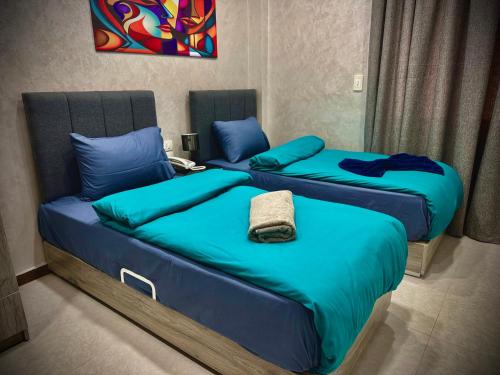 two beds in a room with blue sheets and pillows at Heritage Hostel Cairo in Cairo