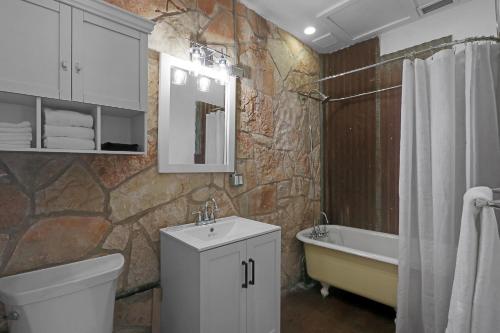 a bathroom with a sink and a toilet and a tub at Milk Bath Springs Cottage in Dripping Springs