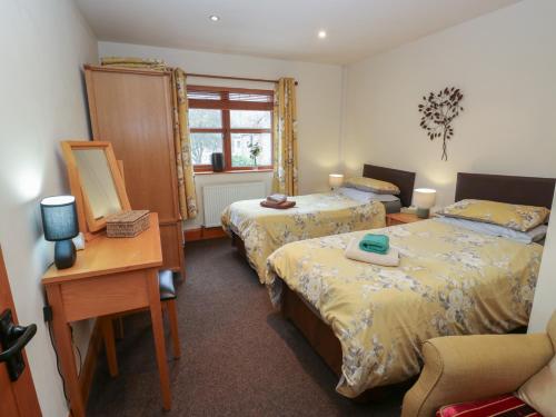a bedroom with two beds and a desk with a mirror at Green Route Apartment in Todmorden