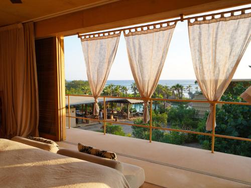 a bedroom with a large window with a view of the ocean at Kymaia Hotel Puerto Escondido in Tlachicón