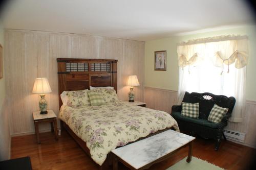 a bedroom with a large bed and a chair at The Inn at Quail Run in Wilmington