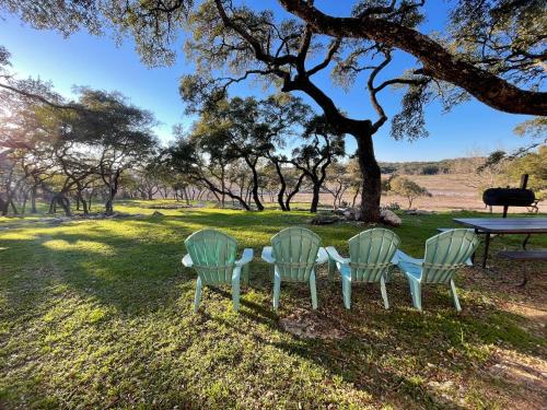three chairs and a table in a field with a tree at Millies Cottages Unit 3 - Phyllis in Canyon Lake