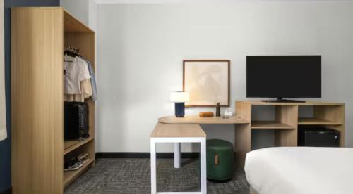 a bedroom with a bed and a desk with a television at Spark by Hilton Charlotte Airport North in Charlotte