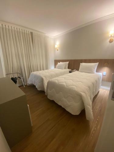 a hotel room with two beds with white sheets at Hotel Cittari Tatuí in Tatuí