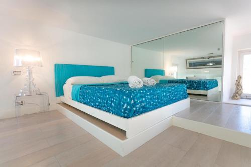 a bedroom with a blue bed with a large mirror at Rooftop luxury apartment in Capri