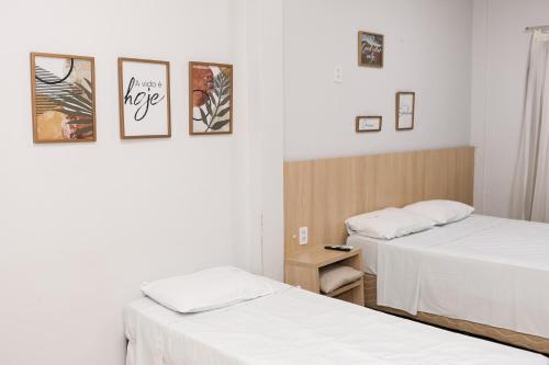 two beds in a room with white sheets at Mais Hotel in Araguaína