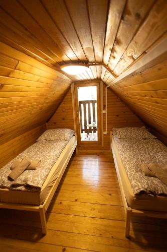 two beds in a wooden room with a window at Marjetina gozdna hiška in Gager