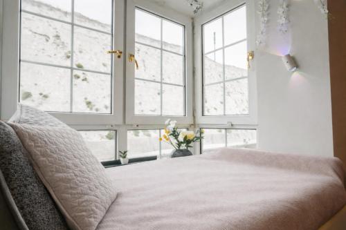 a bedroom with large windows with a bed and flowers at Cozy 1BR Seaside Apt in Brighton Marina Village in Brighton & Hove