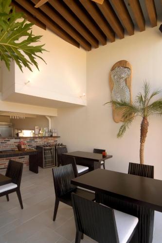 a restaurant with tables and chairs and a palm tree on the wall at Private Resort Hotel RENN in Miyako Island
