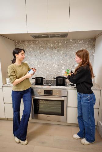 two women standing in a kitchen preparing food at Capsule Residence in Montreal