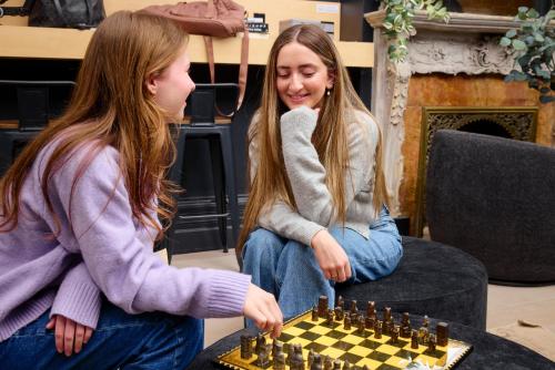 two young women playing a game of chess at Capsule Residence in Montreal