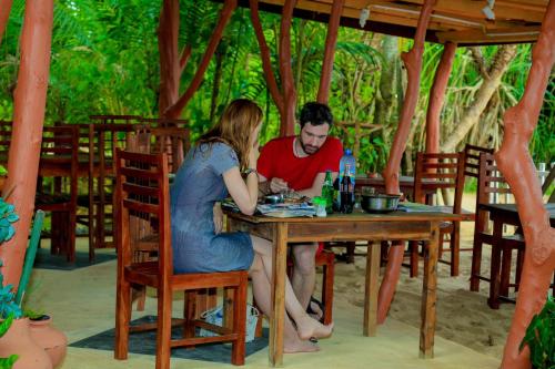 Un uomo e una donna seduti a un tavolo di Mallika Guest House a Tangalle