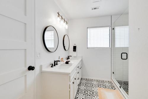 a white bathroom with a sink and two mirrors at Woodacre Cottage in Wimberley