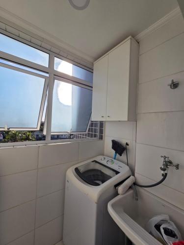 a small bathroom with a washing machine and a sink at terraços do maitinga in Bertioga