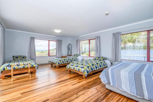 a bedroom with three beds and two windows at Omori Lodge in Tokaanu