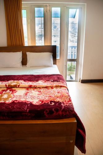 a bedroom with a bed with a red comforter at MGM Daisy Resorts in Nuwara Eliya
