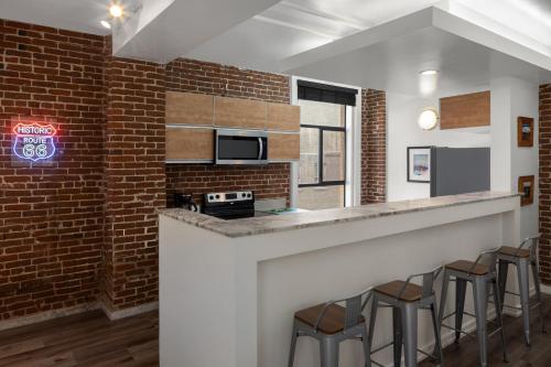 a kitchen with a brick wall and a bar with stools at The Haas, Trademark Collection by Wyndham in Los Angeles