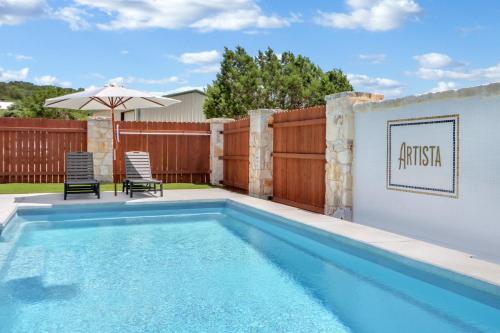 a swimming pool with a fence and an umbrella at Artista in Wimberley