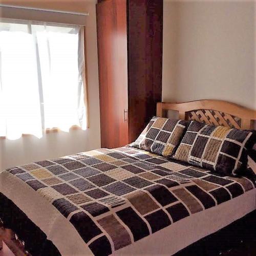 a bedroom with a bed with a checkered blanket at Cabañas Vista Parapentes in Maitencillo
