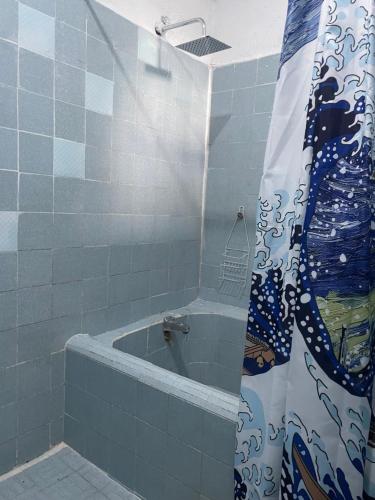a bathroom with a tub with a shower curtain at Casa Malinalli in Zihuatanejo