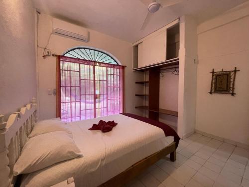a bedroom with a bed with a red ribbon on it at Casa Malinalli in Zihuatanejo