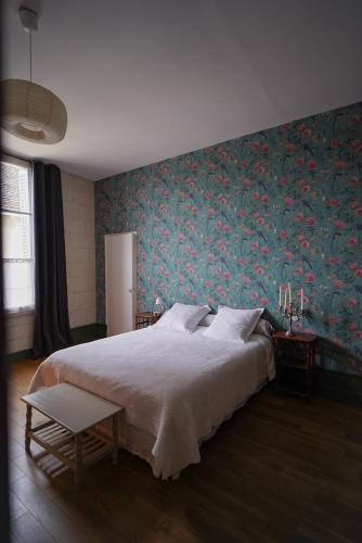 a bedroom with a large bed with a floral wallpaper at La Maison Saint Aignan in Saint-Aignan