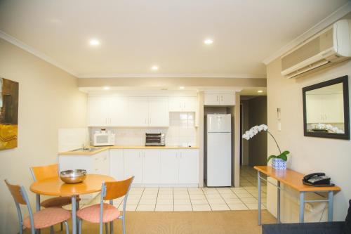 a kitchen with white cabinets and a table and chairs at Cosmopolitan Motel & Serviced Apartments in Rockhampton