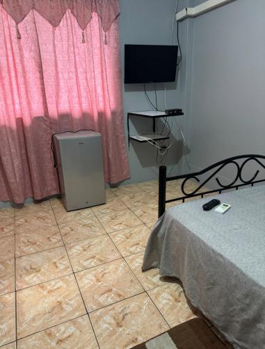 a bedroom with a bed and a television on the floor at Triple K Complex in Kelly Village