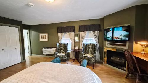 a bedroom with a bed and a tv and a living room at Auberge Wild Rose Inn in Moncton