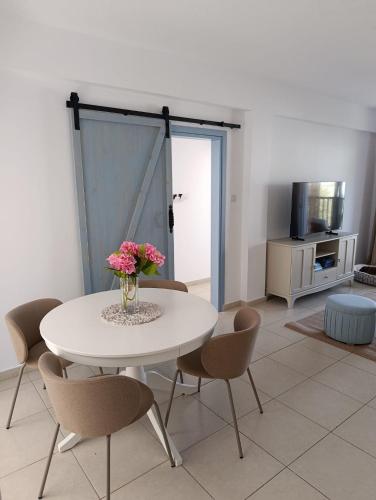 a white table with chairs and a vase of flowers at Aphrodite Breeze Paphos Gardens in Paphos