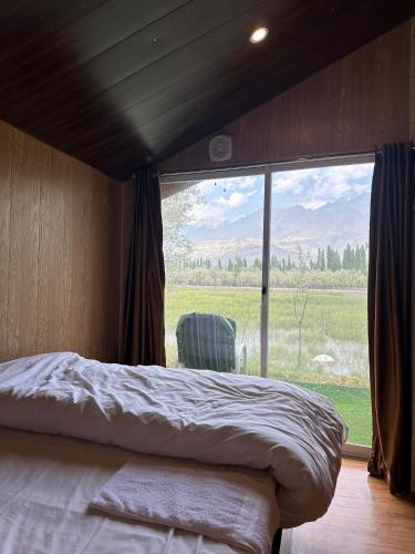 a bedroom with a bed and a large window at MONTAGNA PODS,Best resort in skardu , Best Guest house In skardu in Skardu