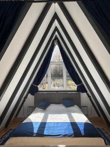 a bed in a tent with a window at NOOR A-frame Sibiu in Gura Râului