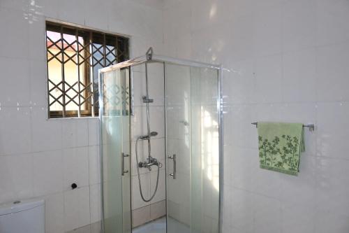 un bagno con doccia con porta in vetro di Lebon Paradise a Accra