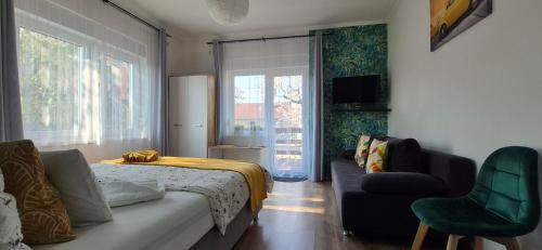a bedroom with a bed and a couch and a window at Bike & Chill Apartment in Balatonfüred