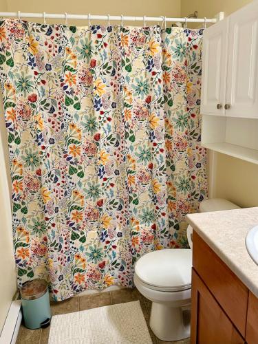 a bathroom with a shower curtain with a toilet at Sunny 1BR by Galloping Goose in Victoria