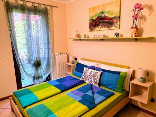 a bedroom with a colorful bed with a window at Casa Raggio di Sole in Toscolano Maderno