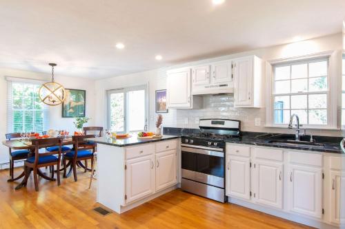 a kitchen with white cabinets and a dining room with a table at Spacious w Beautiful Yard & Dogs Welcome in Harwich