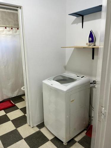 a white toilet in a bathroom with a checkered floor at La casita in Saladillo