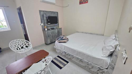 a bedroom with a bed and a chair and a tv at hotel Mansion grand in Khammam