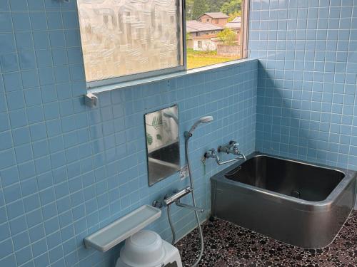 a blue tiled bathroom with a sink and a window at Blue Art Satoyama Retreat in Ōasa