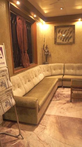 a living room with a large couch in a room at Hotel Shivam in Pune